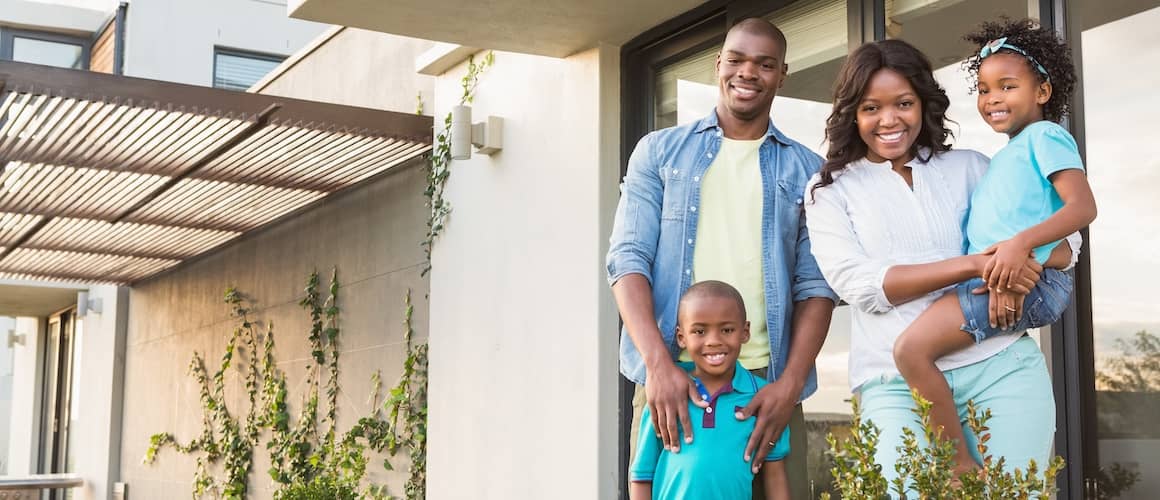 African American family standing in garden outside modern home.