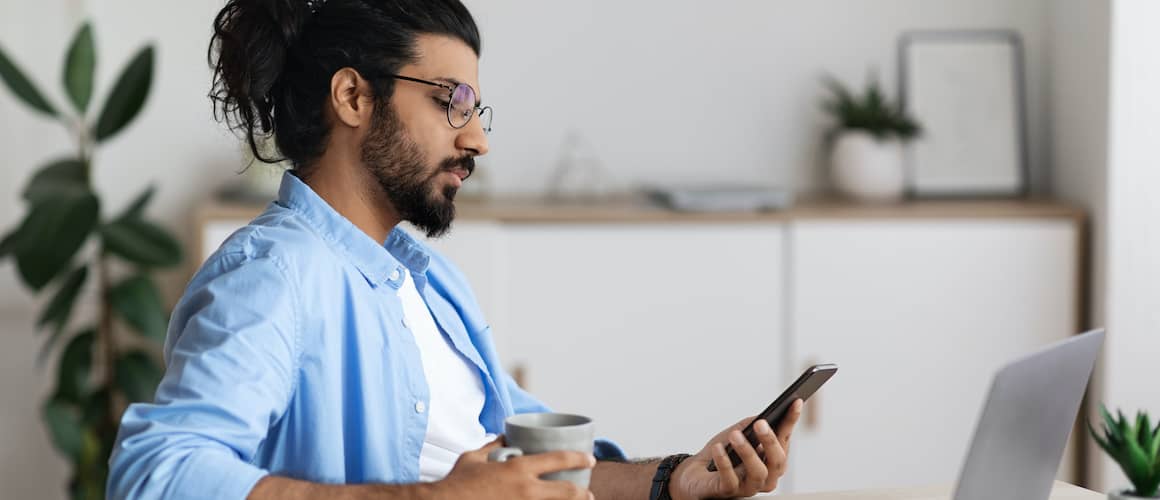 Arab Man With Hair Tied Back Looking At Phone