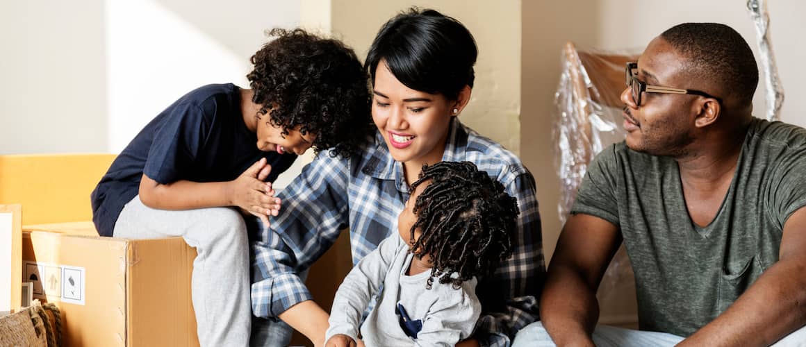 Family with two young boys take a break while unpacking in their new home.