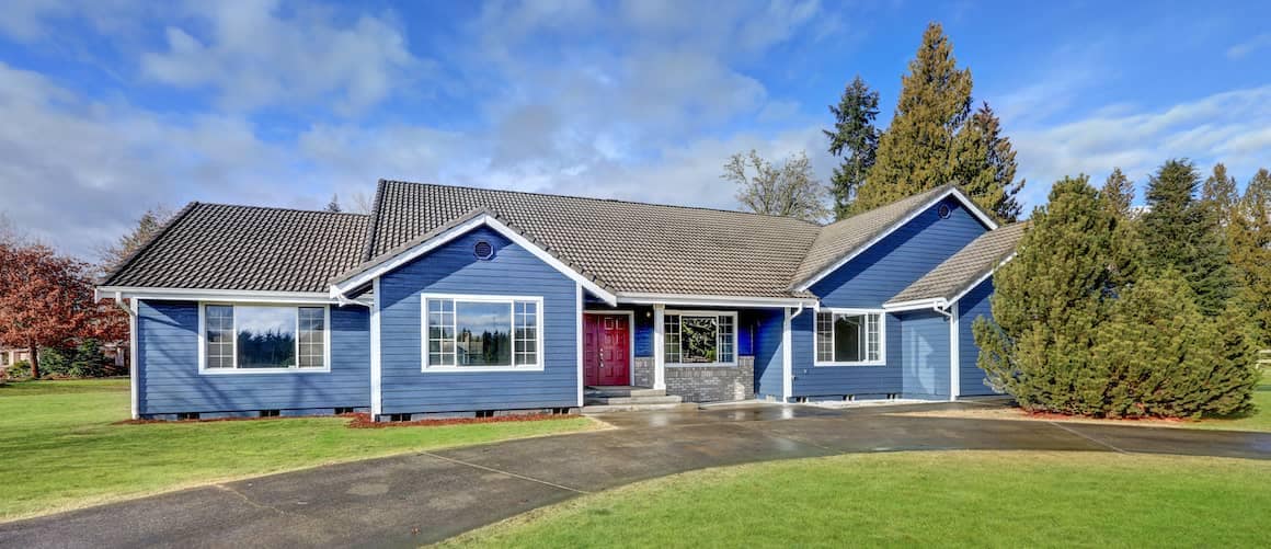 Blue, one-story house with red door, tiled roof and circle drive.