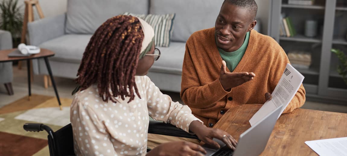 A couple sitting at their kitchen table looking at docs together.