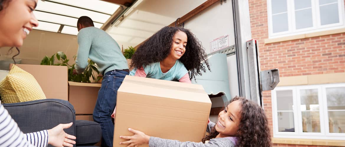 Happy family moving boxes out of moving truck into new home in another state after relocating.