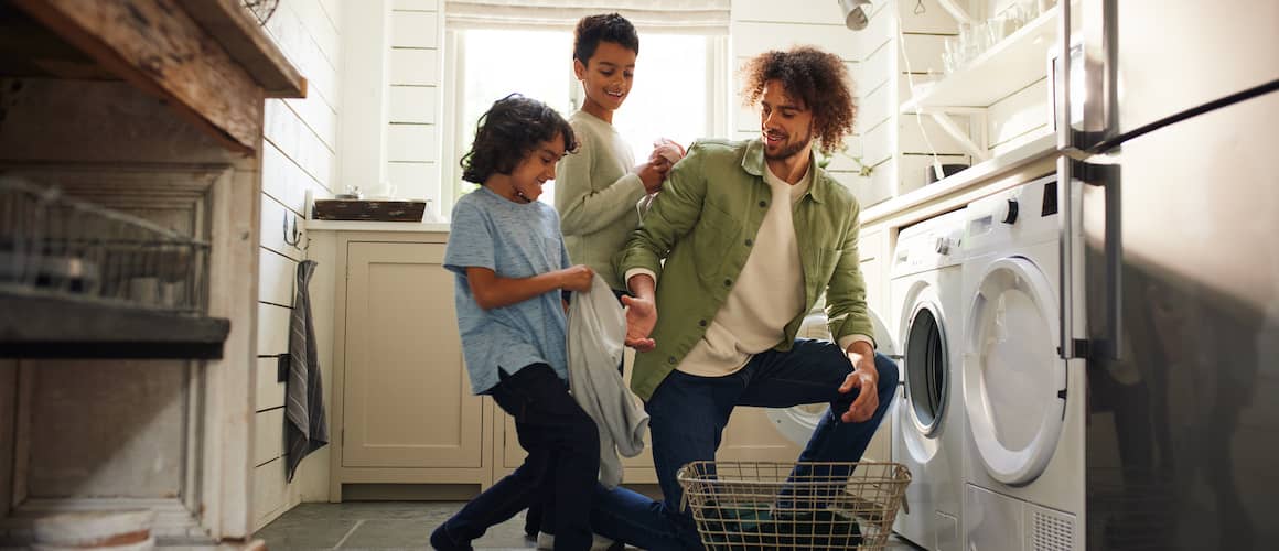 Father doing laundry with his two young sons.