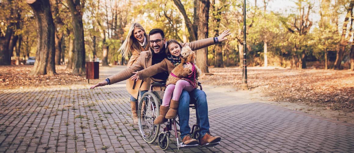 Veteran father in wheelchair plays with daughter and wife in the park.