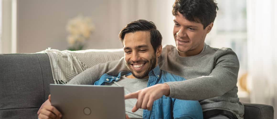 gay couple cuddling on couch with computer