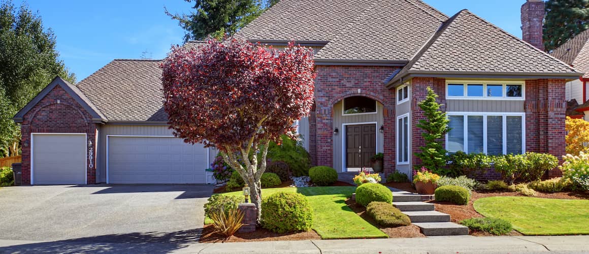 Large suburban home with brick walls and a well-landscaped front yard.
