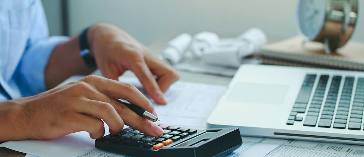 Man using computer and calculator to make calculations.