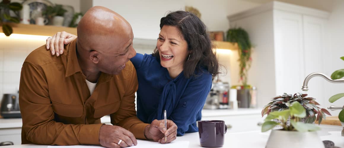 Married couple reviewing mortgage documents on kitchen counter.