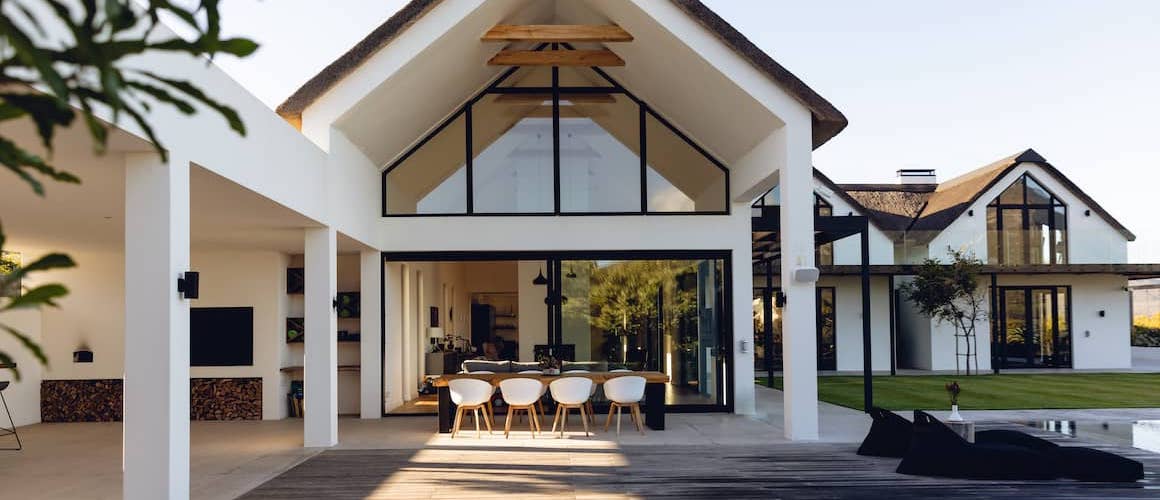 Luxurious white modern house exterior with outdoor dining space.