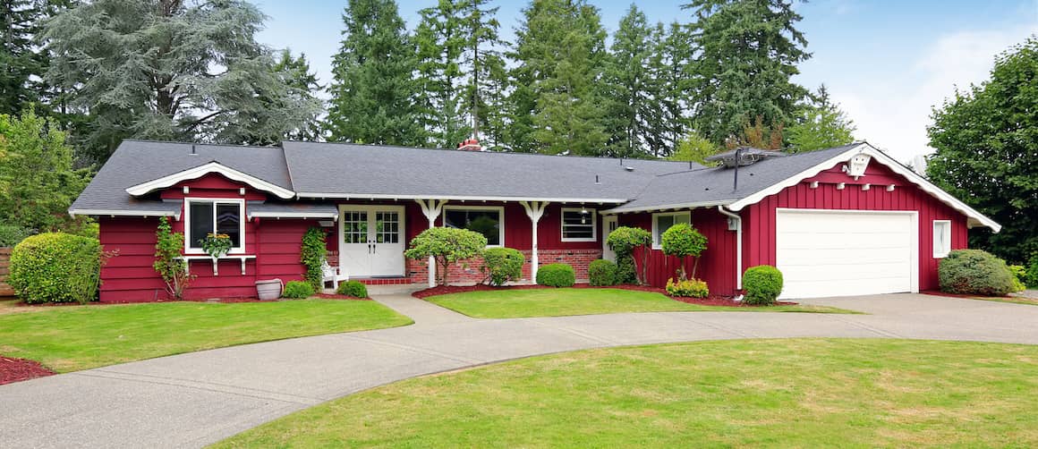 Red, one-story house with white doors, two-car garage and circle drive.