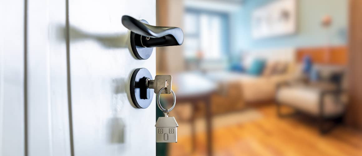 Keys inside lock of a black and white door opening to a living room.