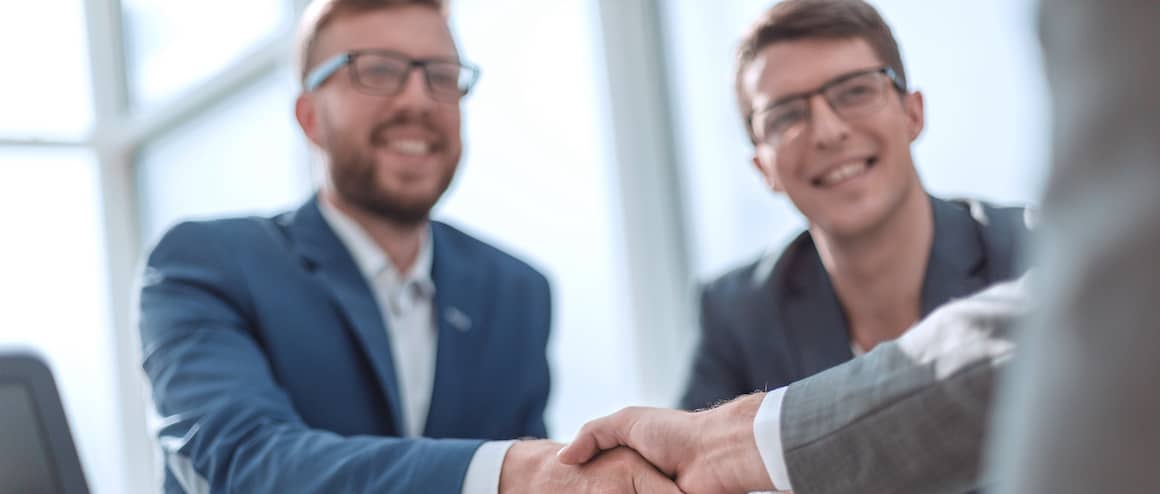 Businessmen shaking hands and smiling.