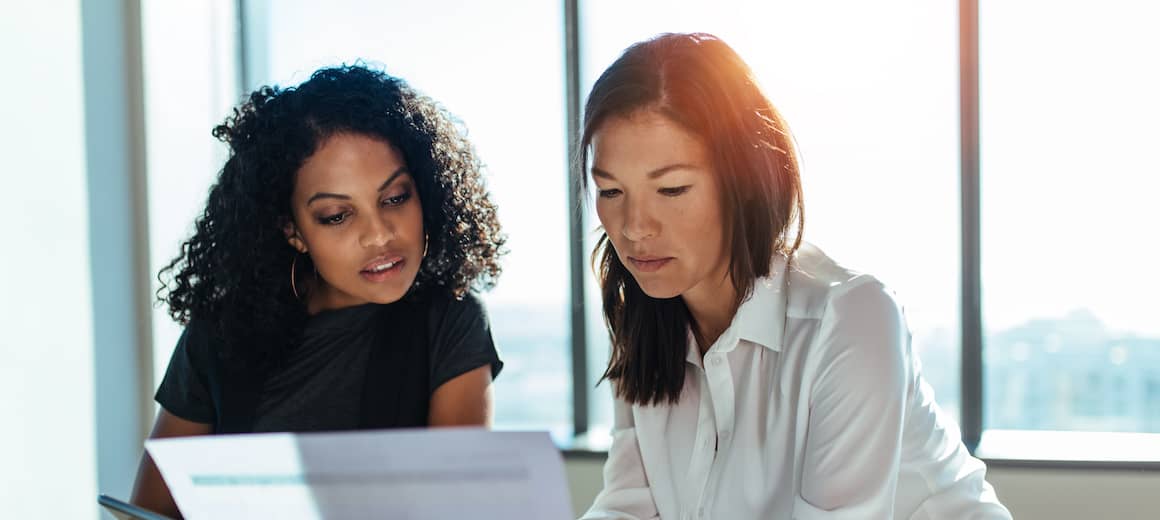 Two women looking at a paper together.