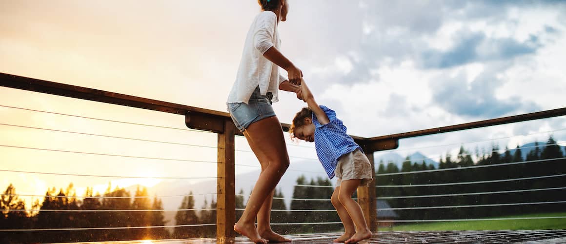Mother and son on back deck overlooking land at sunset.