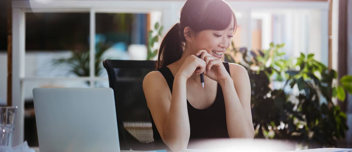 Woman smiling, looking at deed to new home on desk.