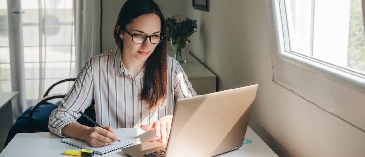 woman researching and writing on notepad