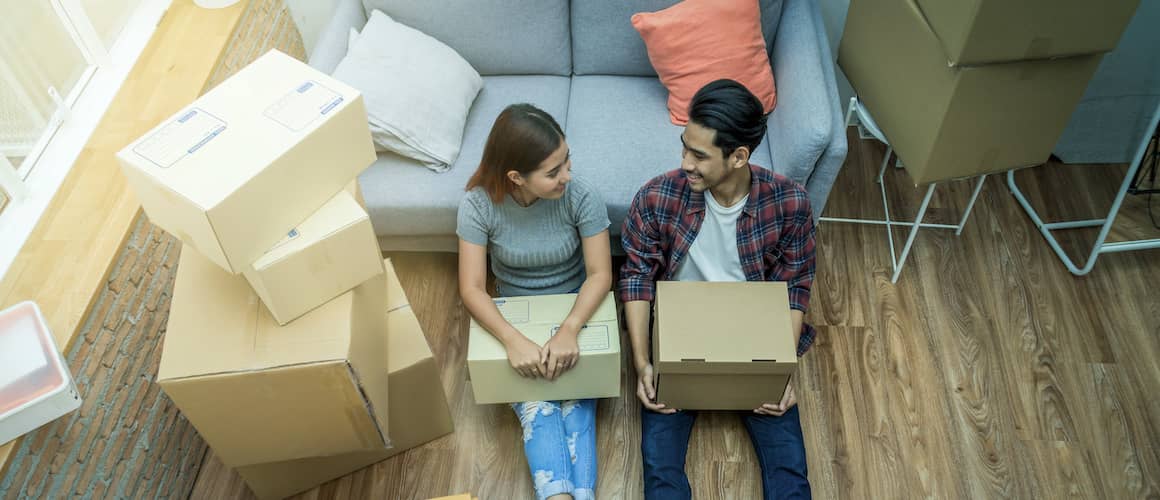Young Asian couple take a break from unpacking boxes in new home.