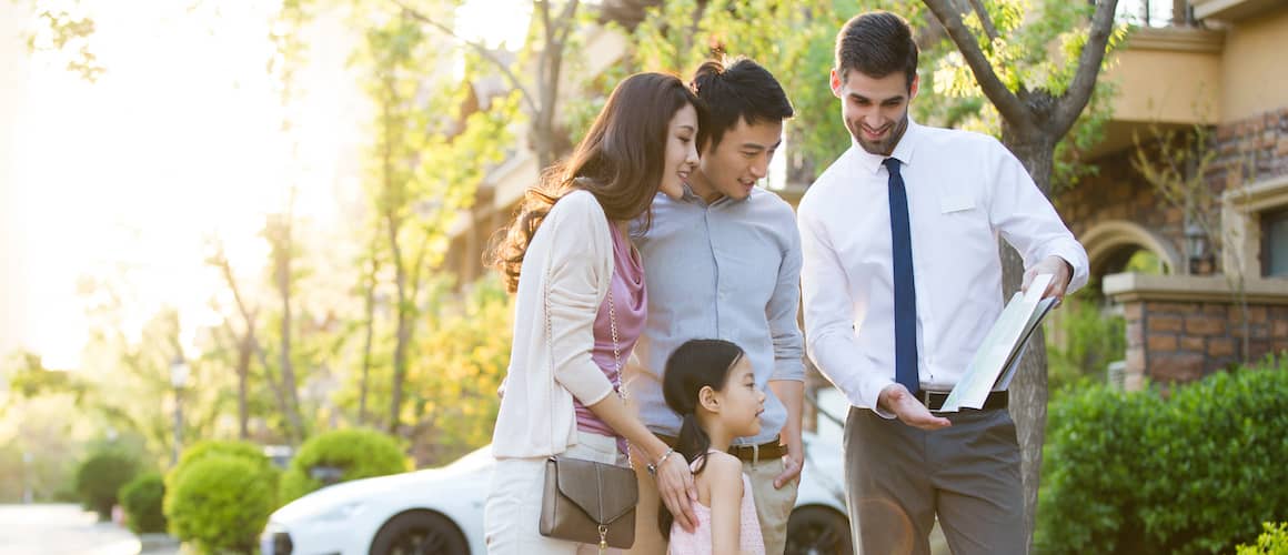 Young Asian family looks at Real Estate paperwork together after purchasing a home.