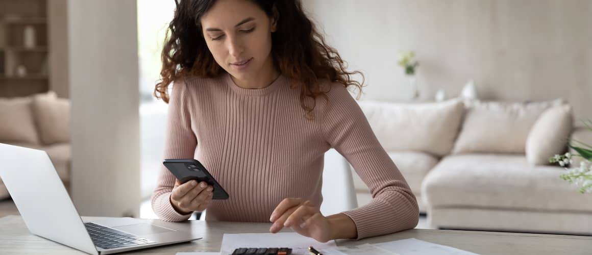 Young Woman Sitting At Desk Paying Bills