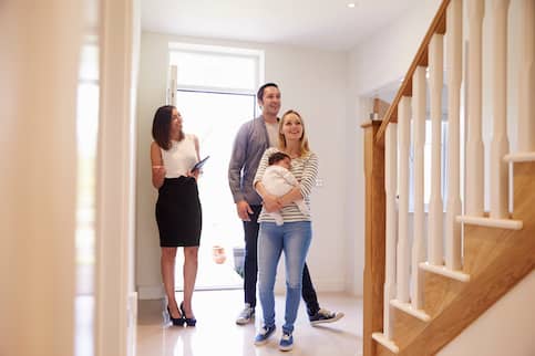 Young family with baby looks at new home.