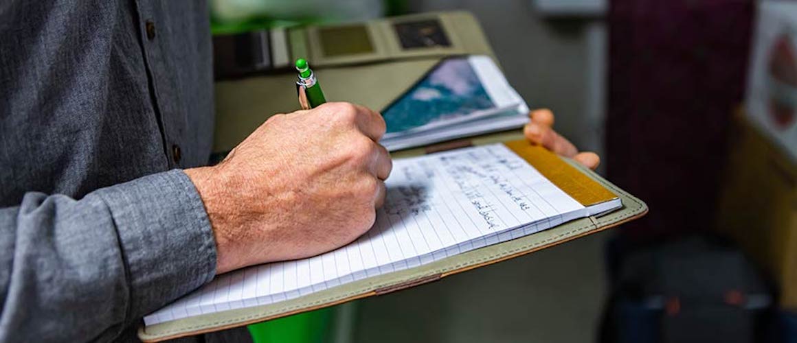 Home inspector writing on clipboard.