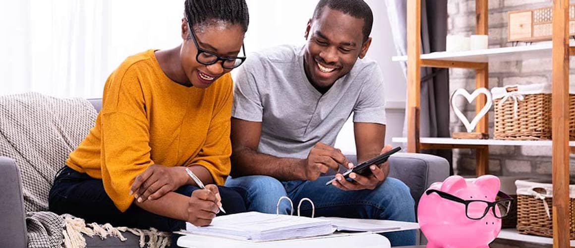 Couple smiling doing financial planning on couch.